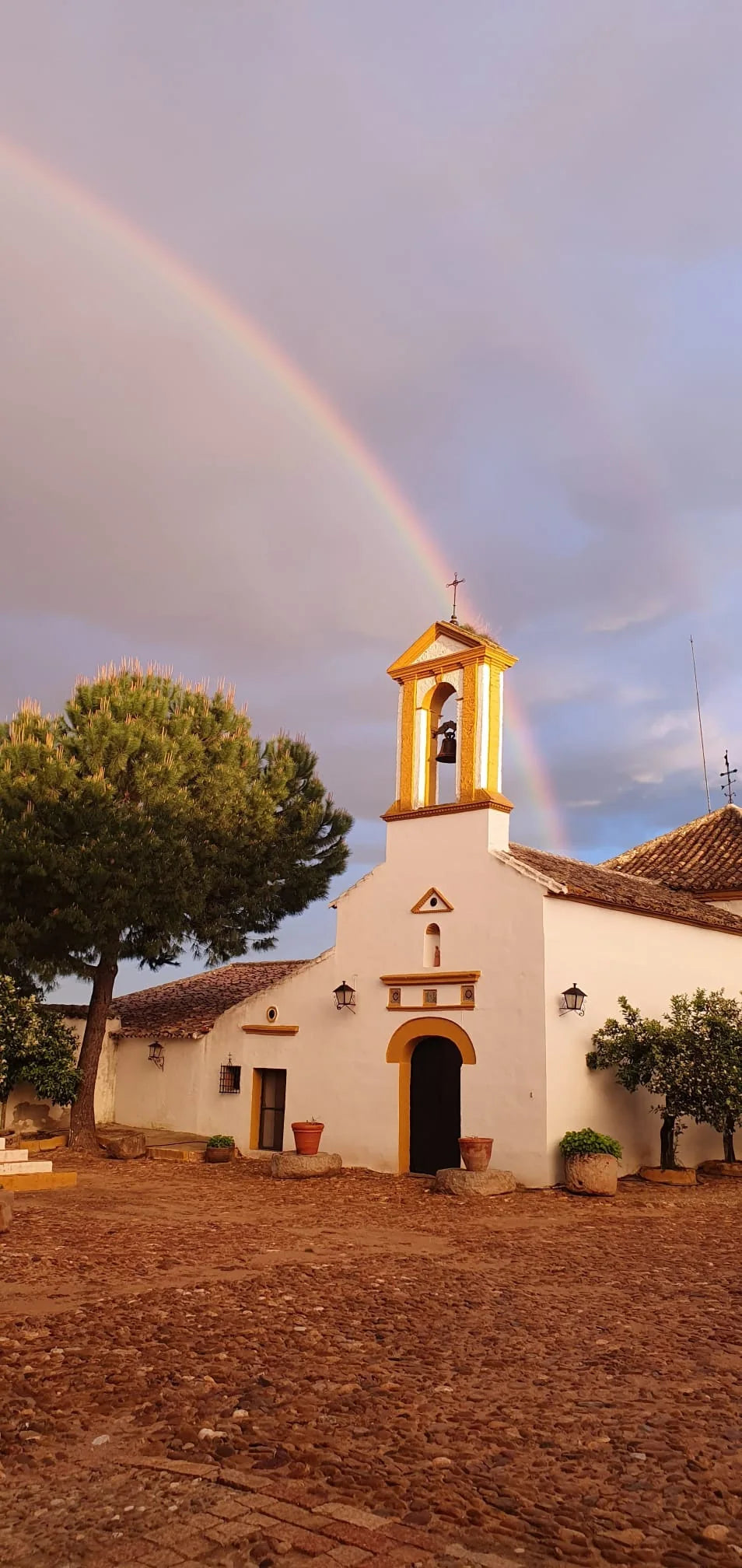 Cortijo de la Aldehuela al atardecer con arcoíris sobre el campanario